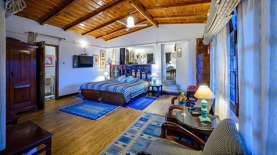 A second bedroom in Magnolia with two chairs in front of the window and an ensuite bathroom - Ramgarh Bungalows, Nainital.