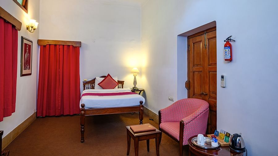 An overview of the Maharajkumari Surinder Kaur room with a double bed, a chair and a small table - The Baradari palace