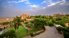Facade view of Tijara Fort-Palace - 19th Century, Alwar, with a cloudy blue sky in the background.