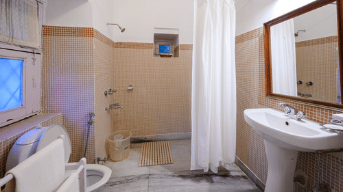 Side view of a Washroom with curtains around the shower area - Ramgarh Bungalows, Nainital.