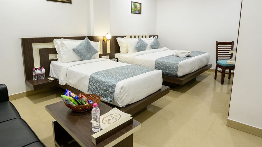 Side view of Family Room featuring two beds of different sizes, a central bed lamp, and stylish interior design at Biznotel by Pride, Deoghar.