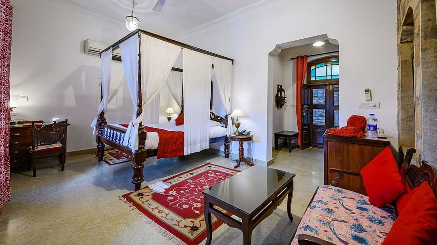 Deo Bagh - 17th Century, Gwalior - a king size bed covered with sheets kept beside a sofa set at the Jayaji Vilas - Naubagh / Garden View room in Gwalior