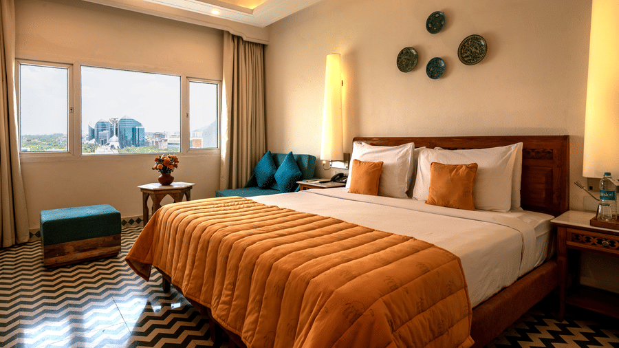 Club room's bedroom at Clarks Group of Hotels featuring a king-size bed, patterned flooring, warm lighting, seating area and city view window.
