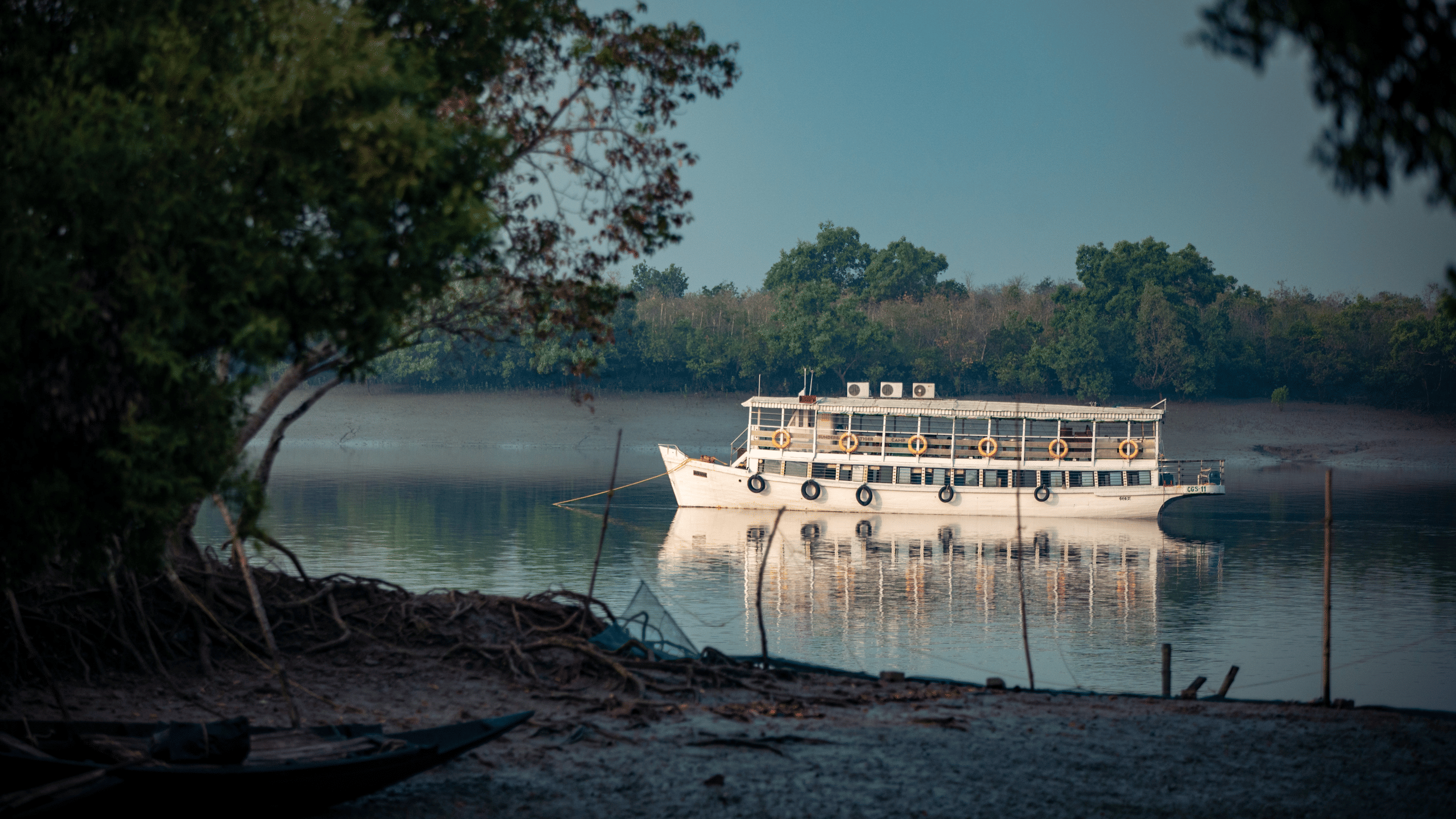 Boat floating in a lake which is surrounded by trees on all sides.
