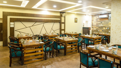 Side view of the restaurant featuring stylish interior design and table arrangements at Biznotel by Pride, Deoghar