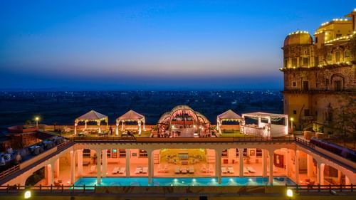An elevated view of a rectangular pool with tented structures alongside a building at Tijara Fort-Palace - 19th Century, Alwar.