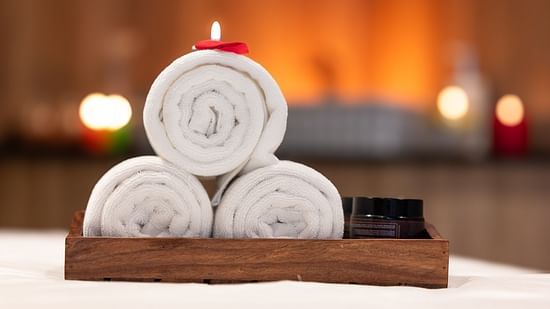 An image of three towels rolled in a wooden tray - The Manor Luxury Hotel, Shimla