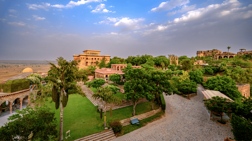 Facade view of Tijara Fort-Palace - 19th Century, Alwar, with a cloudy blue sky in the background.