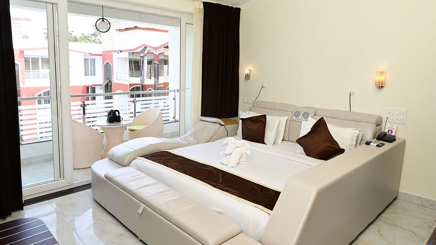 a modern bed with floor to ceiling glass sliding doors inside one of the rooms at VITS shanti solitaire, North Goa