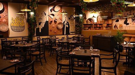 An image of a cafe with several sets of tables and chairs and the walls are  painted with doodles - Essentia Premier Hotel, Chennai.