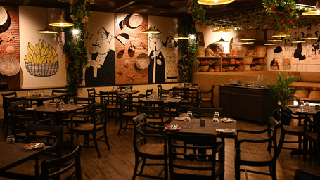 Fisherman's Wharf with several sets of tables and chairs and the walls painted with doodles at Essentia Premier Hotel, Chennai, one of the best places in Chennai for team outings