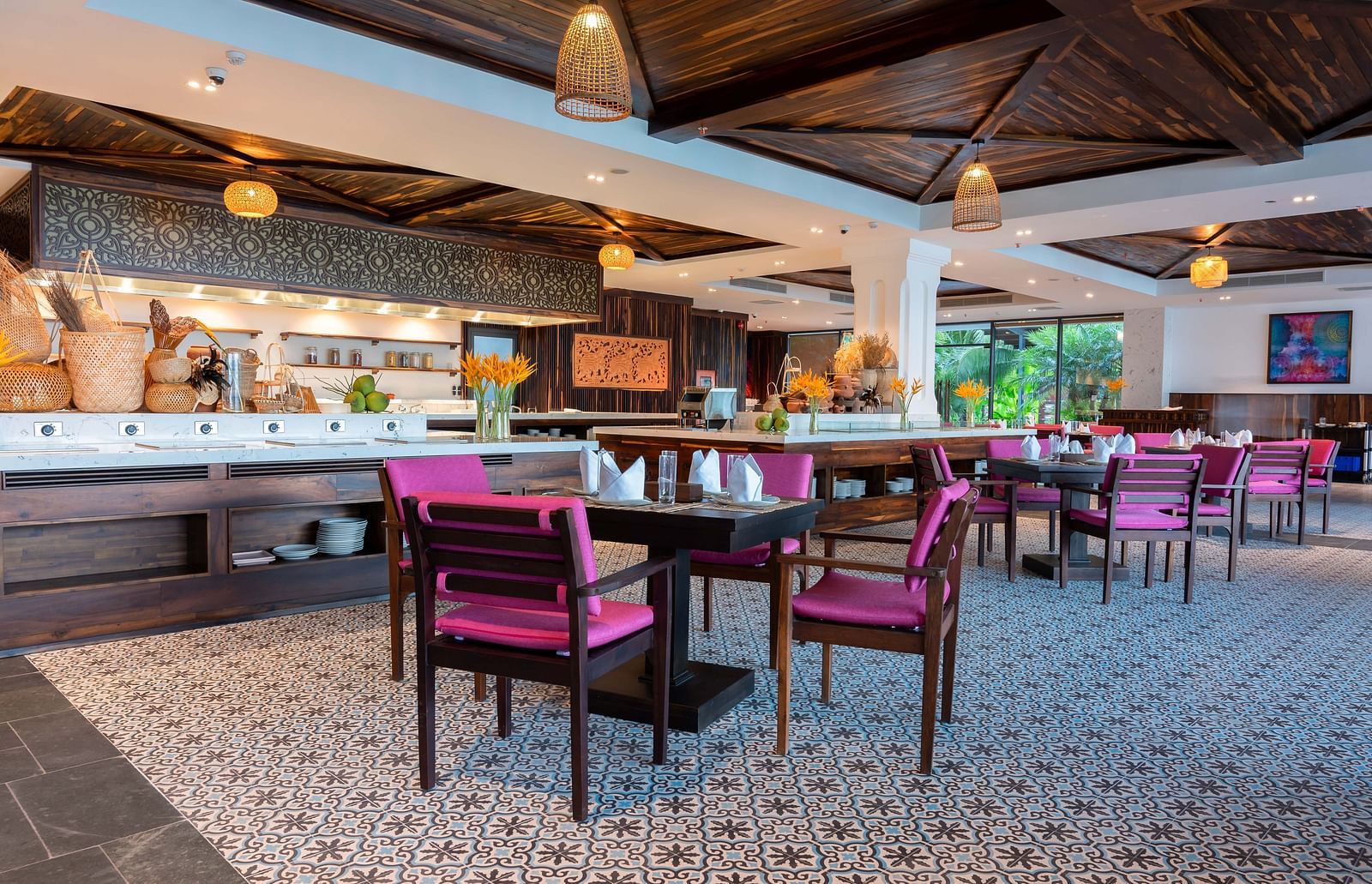A restaurant with flower printed tiles, wooden chairs. lamps hanging from the ceiling and a bar counter - Alibu Resort Nha Trang