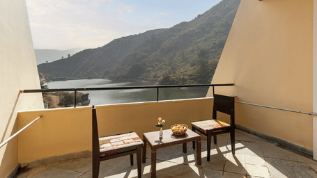 A balcony view with neatly arranged table and chairs under a sunny day -  Via Lakhela Lakeview Resort