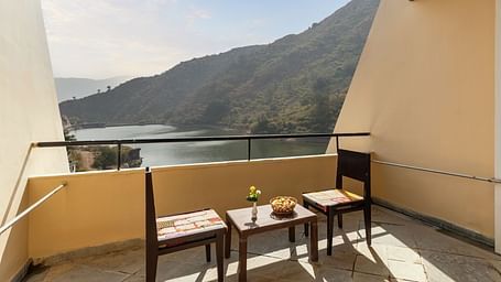A balcony view with neatly arranged table and chairs under a sunny day - Via Lakhela Resort & Spa