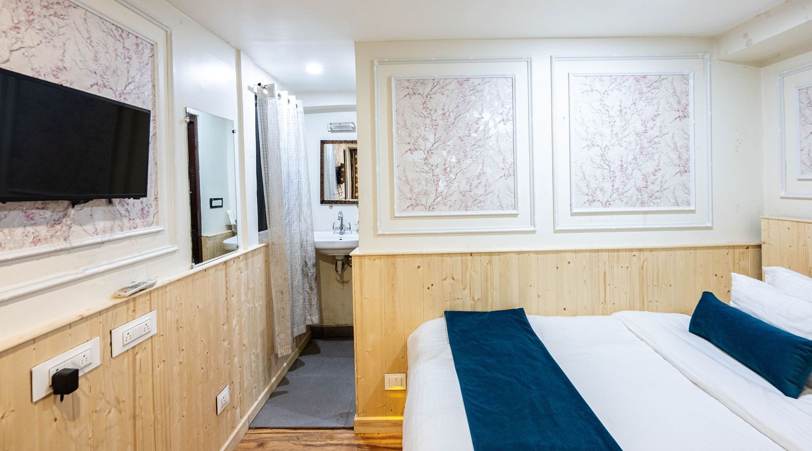 an image of  a deluxe room with a king size bed and a wall mounted television opposite to it at Avianna New Mandala Hotel & Spa, Darjeeling 