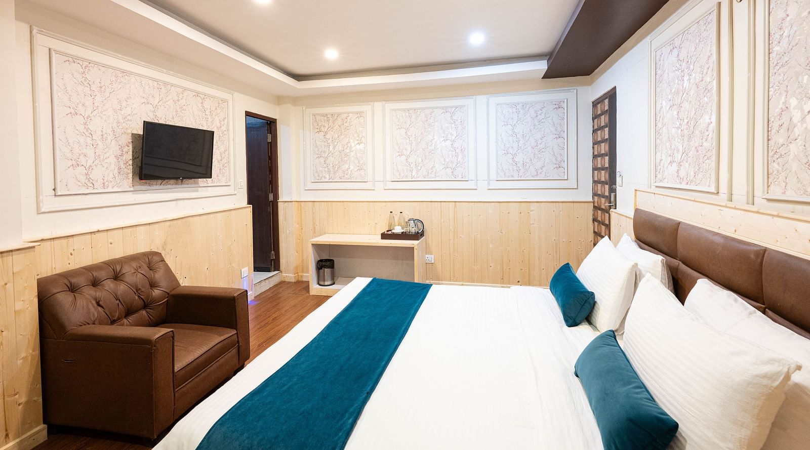 an image of a deluxe room with a cushioned chair and a wall mounted television at Avianna New Mandala Hotel & Spa, Darjeeling