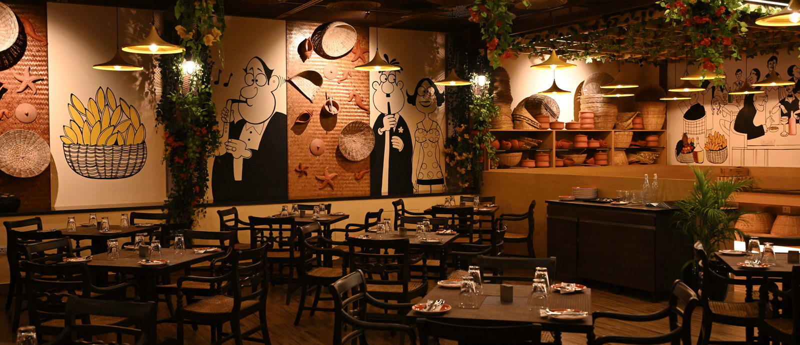 A cafe with several sets of tables and chairs and the walls painted with doodles at Essentia Premier Hotel, Chennai