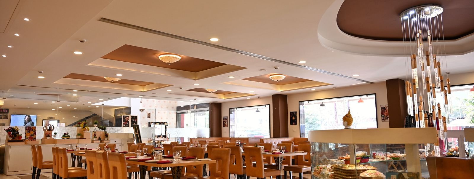 Hotel dining area with neatly arranged tables, contemporary art and a service counter - TGI Insignia, Bhopal