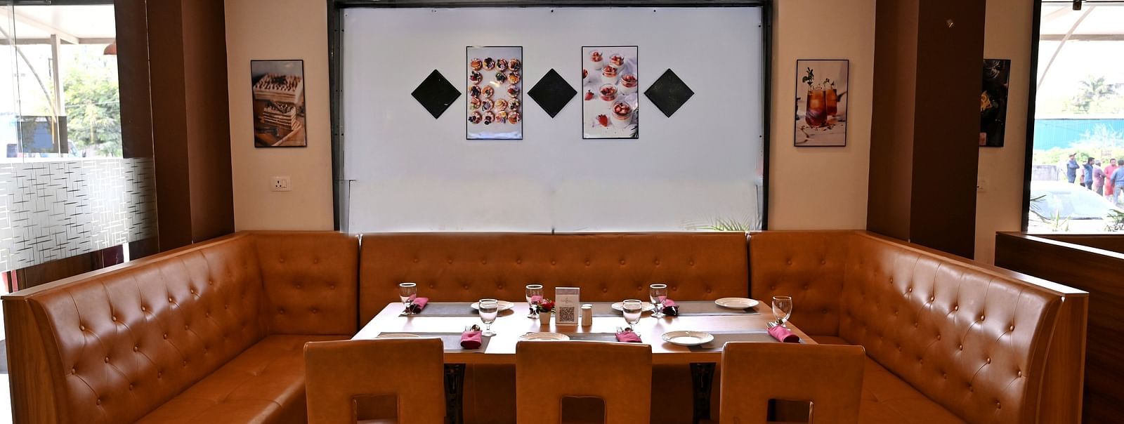 Cosy dining corner with a brown leather booth and wooden tables in a restaurant - TGI Insignia, Bhopal