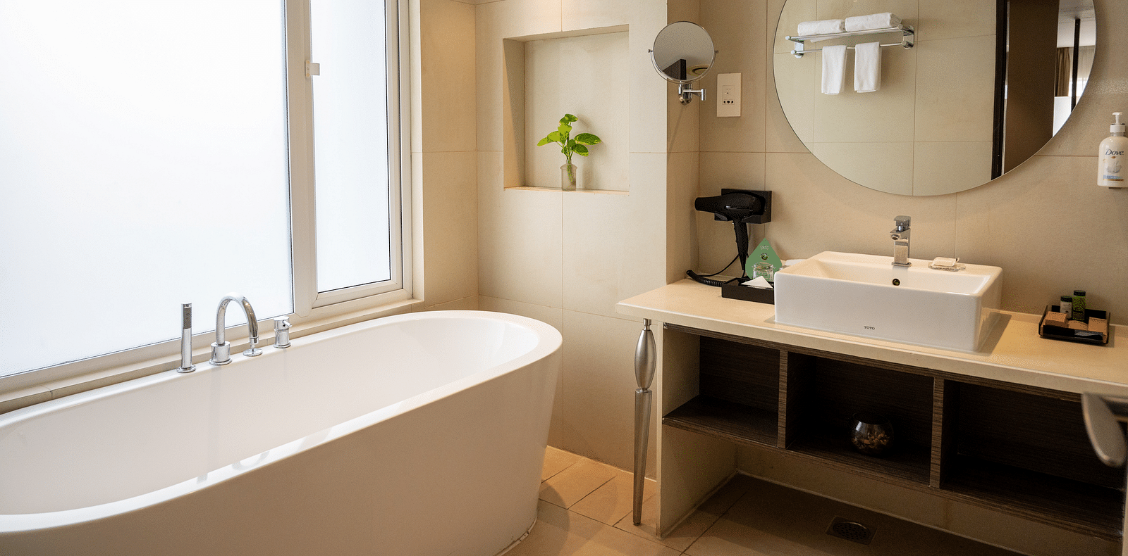 An image of a bathroom with a bath tub and a mirror at Grand Kakinada by GRT Hotels