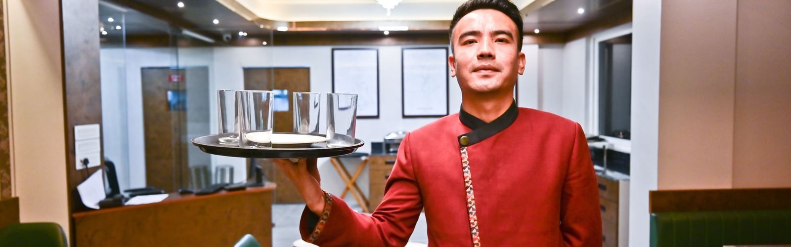 The waiter elegantly holding the dishes, prepared to serve, at The Soma Hotel by Avianna Group, Darjeeling