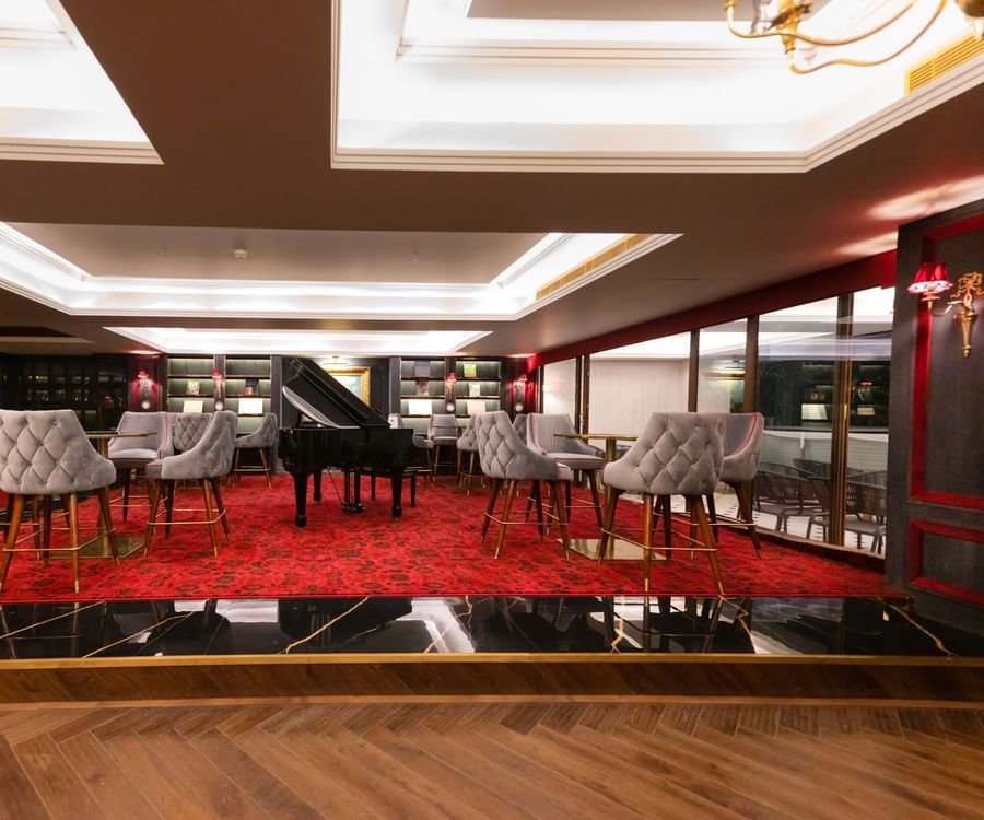 A platform with a tables and chairs placed around a giant piano in Stable restaurant - The Manor Luxury Apartment, Shimla 