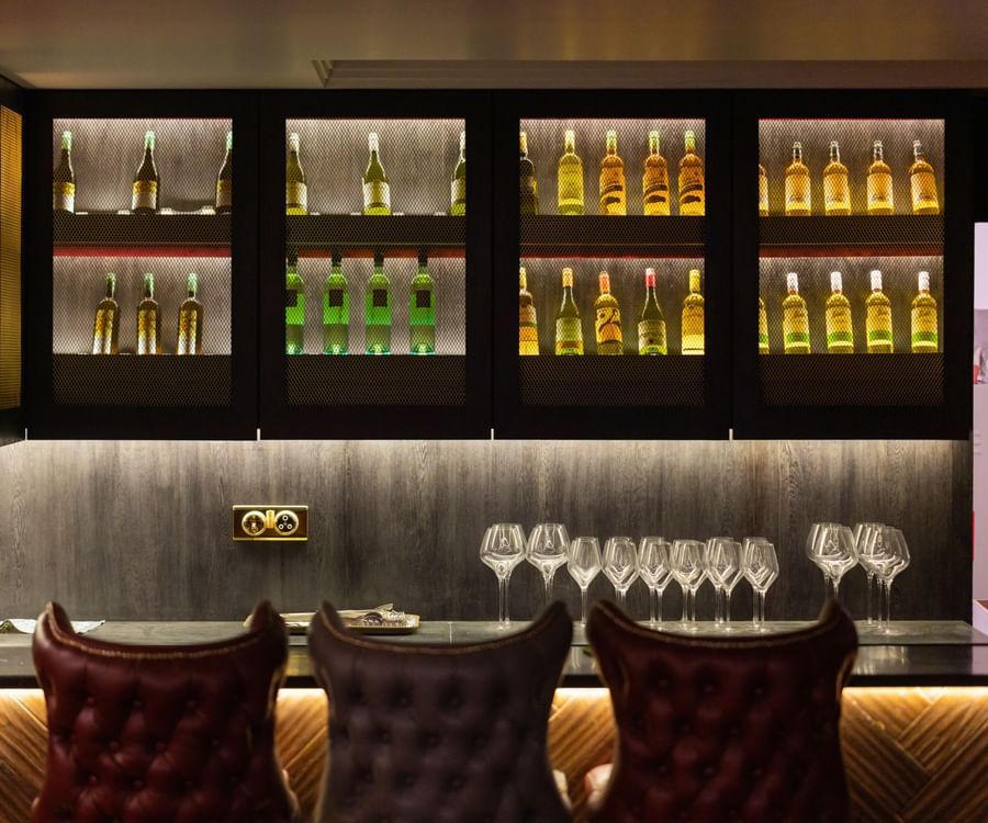A bar counter at the restaurant with champagnes placed in cupboards - The Manor Luxury Hotel, Shimla