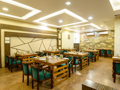 Side view of the restaurant featuring stylish interior design and table arrangements at Biznotel by Pride, Deoghar
