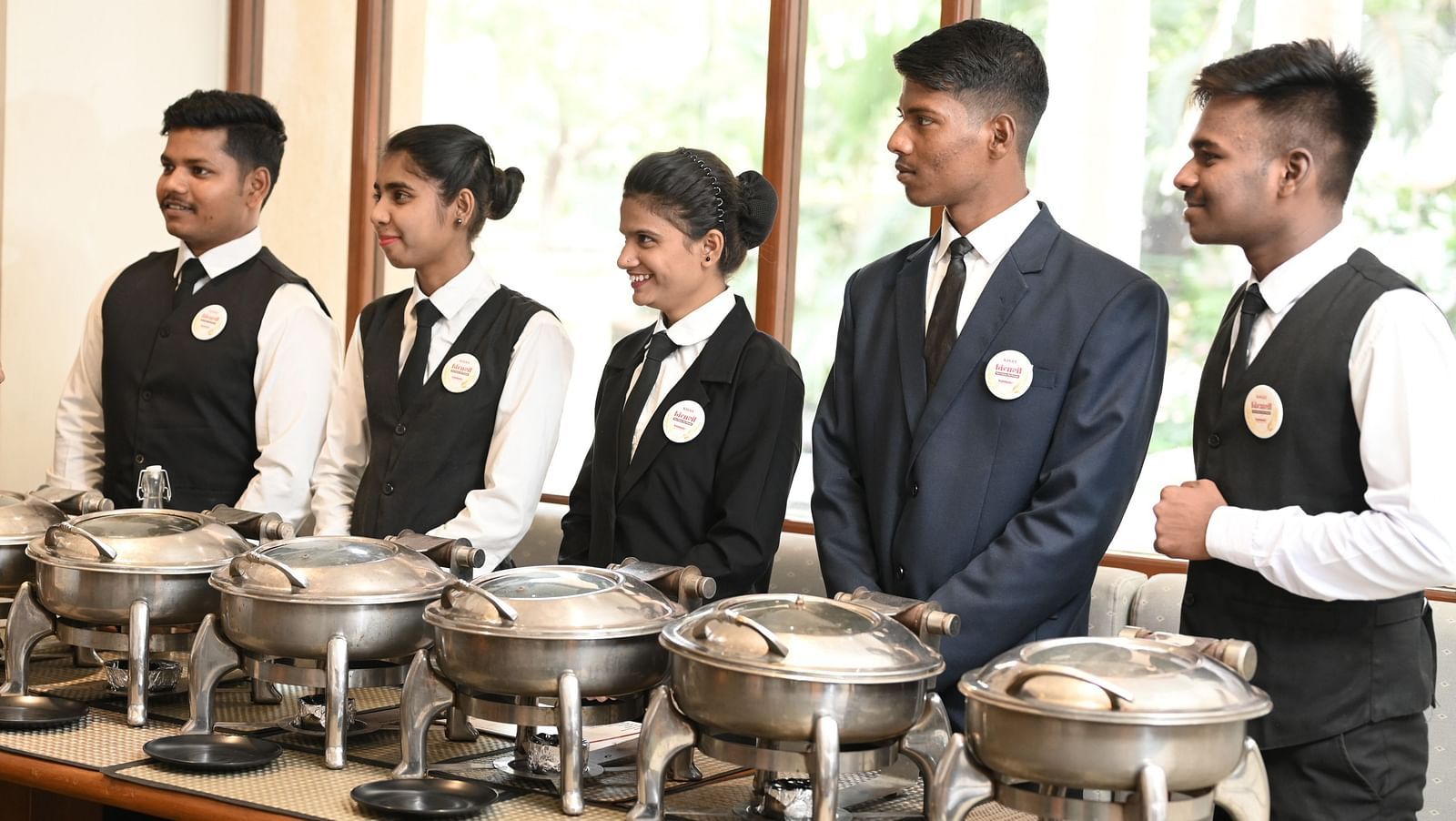 A hotel chef and manager briefing restaurant staff beside a buffet setup - Kamats India
