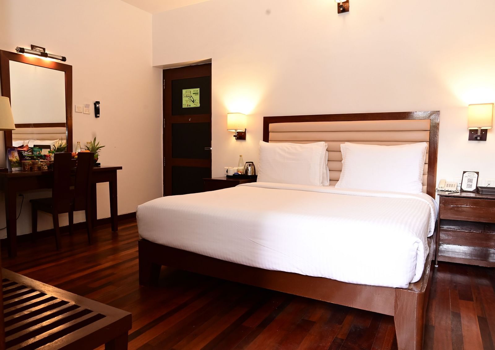 An image of a room with a king size bed, bed side table, lamps, dressing table, and a chair - GReaT trails Kodaikanal by GRT Hotels