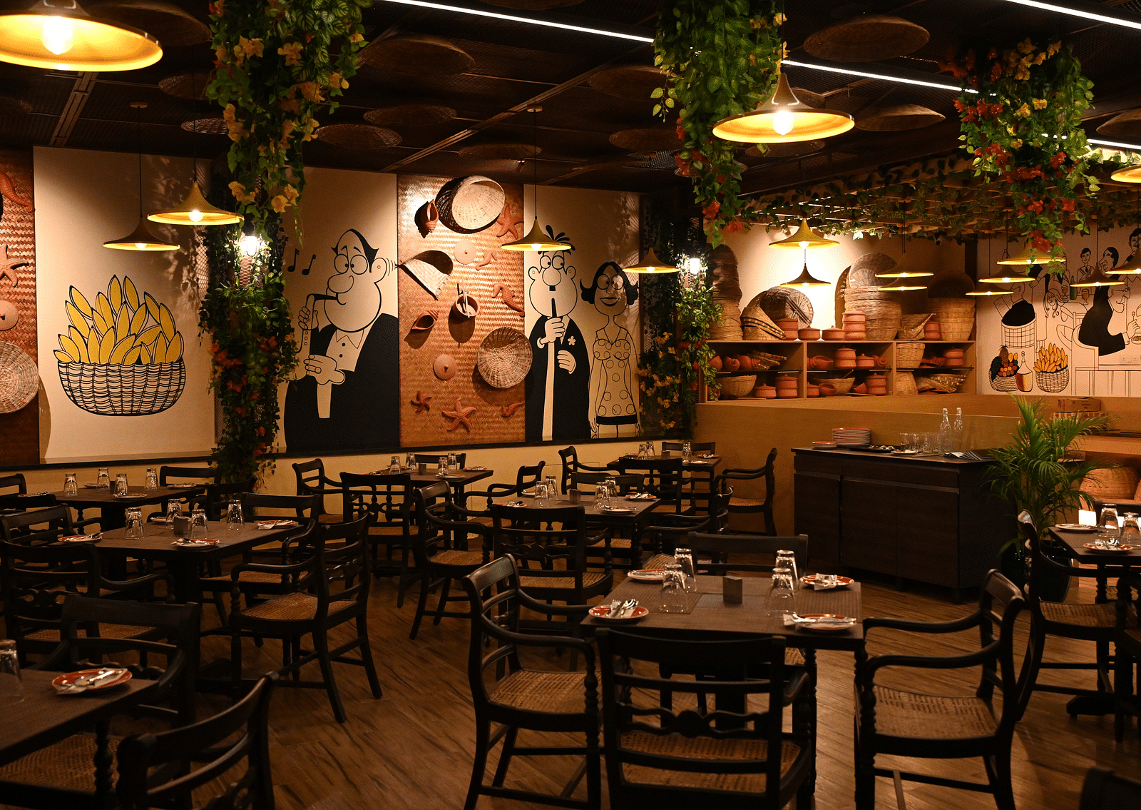 An image of a cafe with several sets of tables and chairs and the walls are  painted with doodles - Essentia Premier Hotel, Chennai.