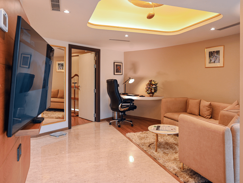 Suite living area with a comfortable sofa, work desk, and wall-mounted TV at Dimora Hotels and Resorts, offering a relaxing and functional space.