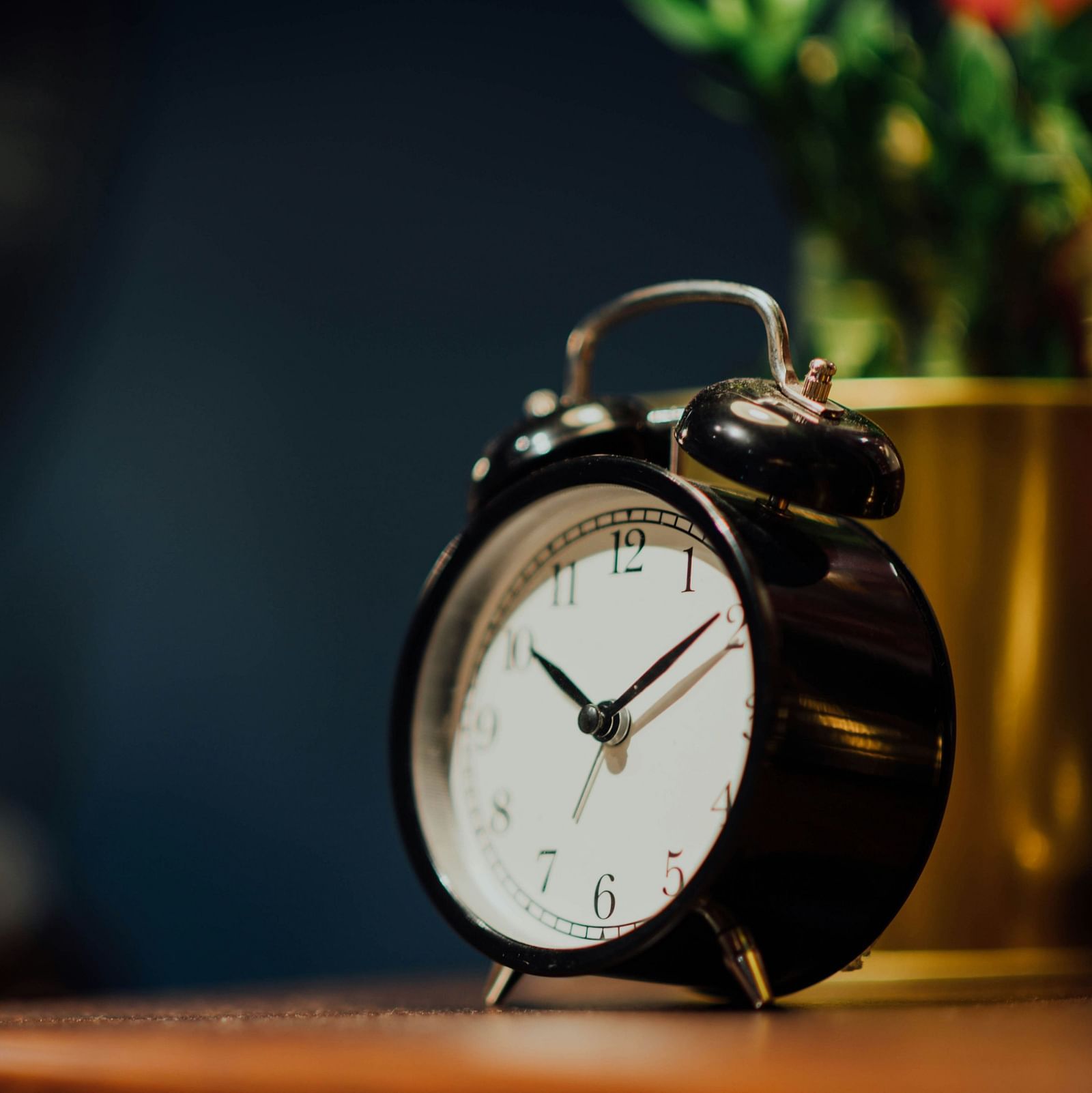 A clock is kept on the table striking 10:10 and blur blackdrop