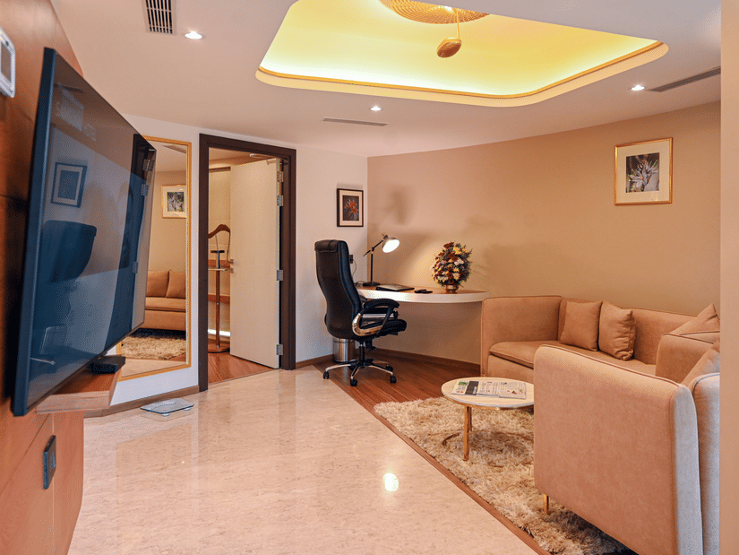 Suite living area with a comfortable sofa, work desk, and wall-mounted TV at Dimora Hotels and Resorts, offering a relaxing and functional space.