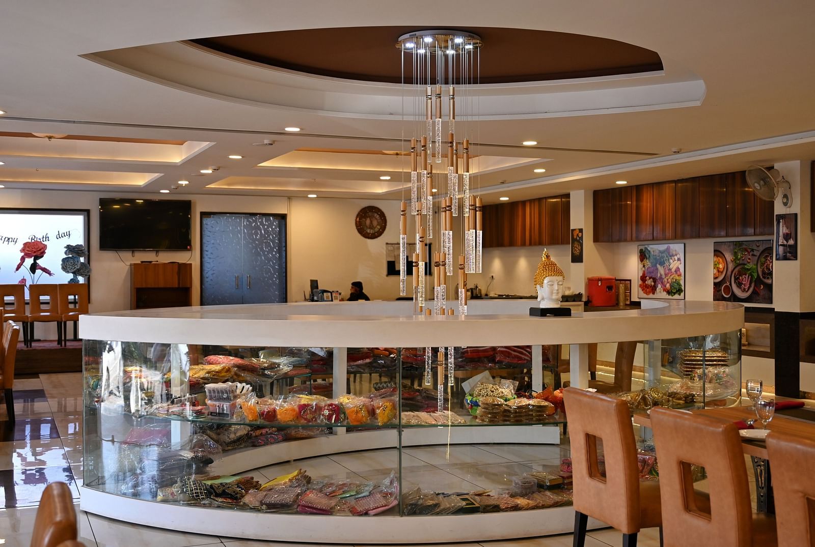 Another view of a hotel restaurant interior with circular centre piece display under a modern chandelier - TGI Insignia, Bhopal