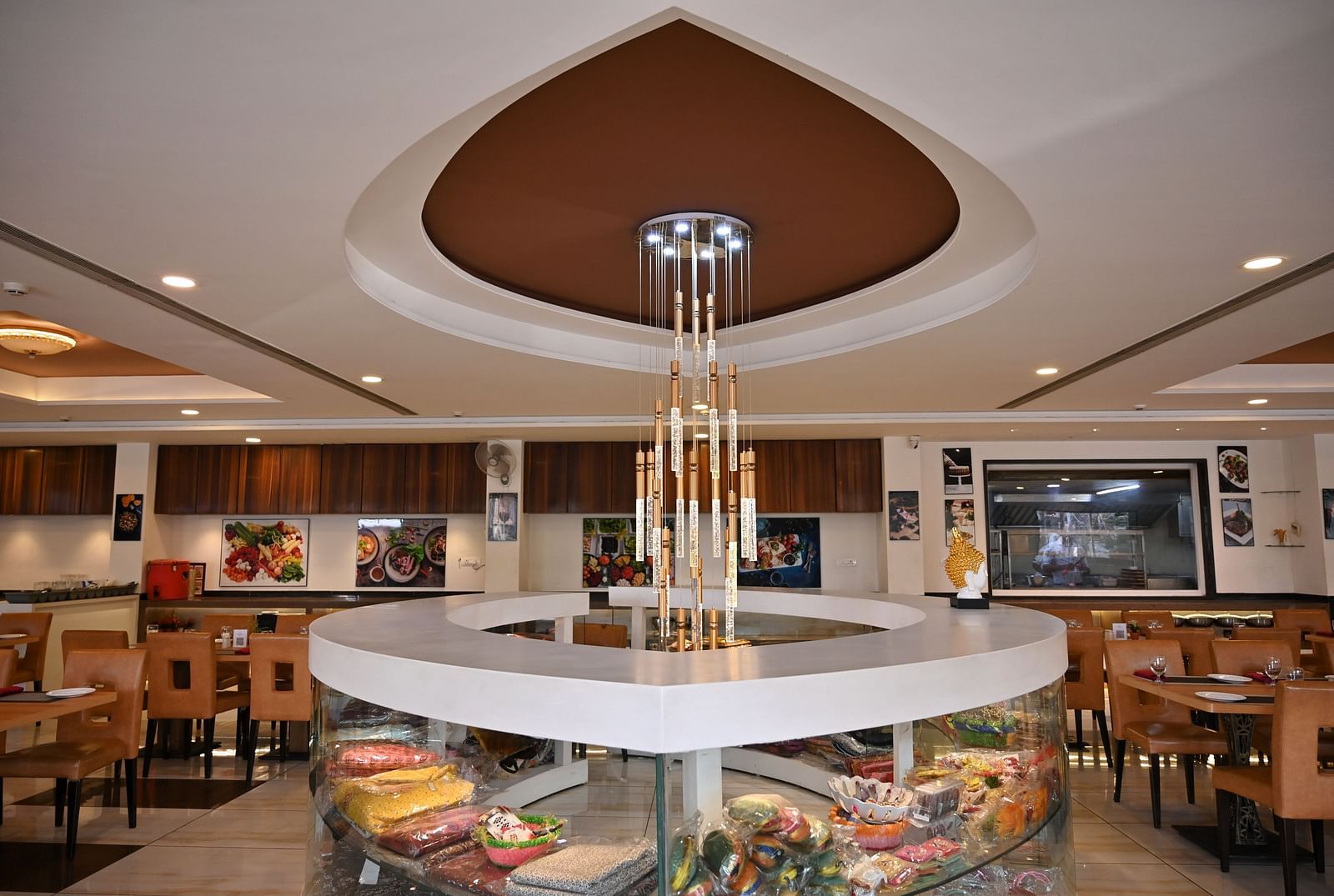 Hotel restaurant interior with circular centre piece display under a modern chandelier - TGI Insignia, Bhopal
