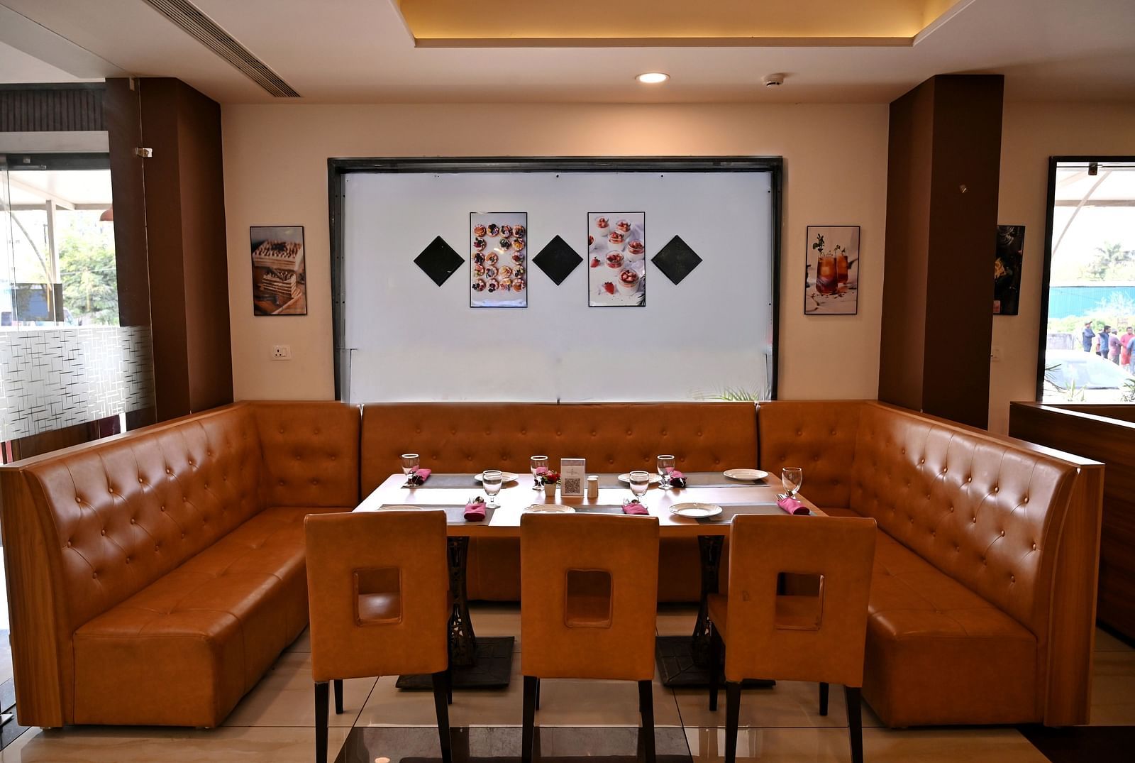 Cosy dining corner with a brown leather booth and wooden tables in a restaurant - TGI Insignia, Bhopal