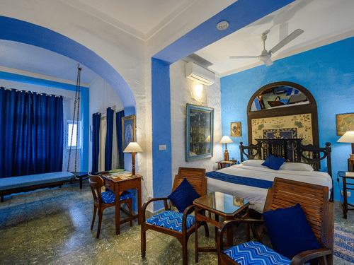 Hindola Mahal - Countryside View room with blue decor brown chairs and a bed at Hill Fort-Kesroli - 14th Century, Alwar
