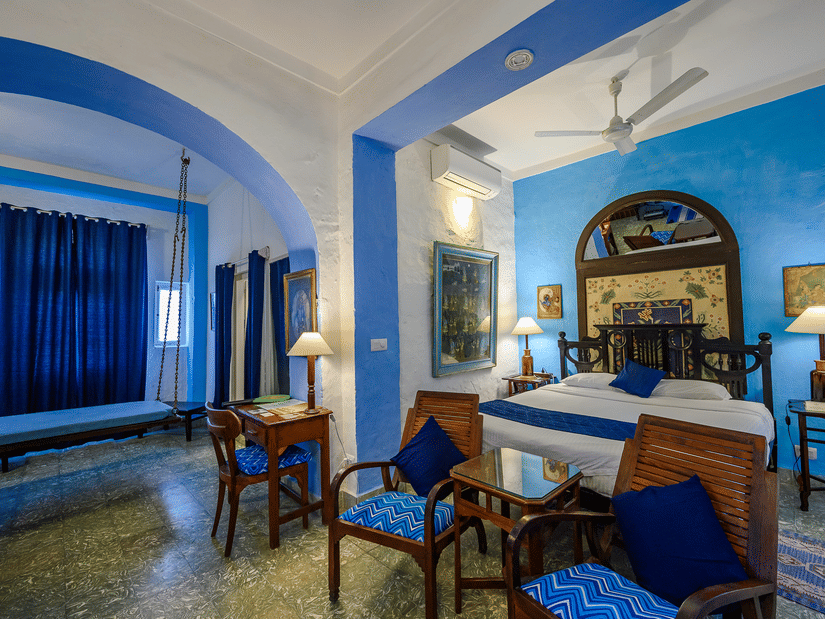 Hindola Mahal - Countryside View room with blue decor brown chairs and a bed at Hill Fort-Kesroli - 14th Century, Alwar