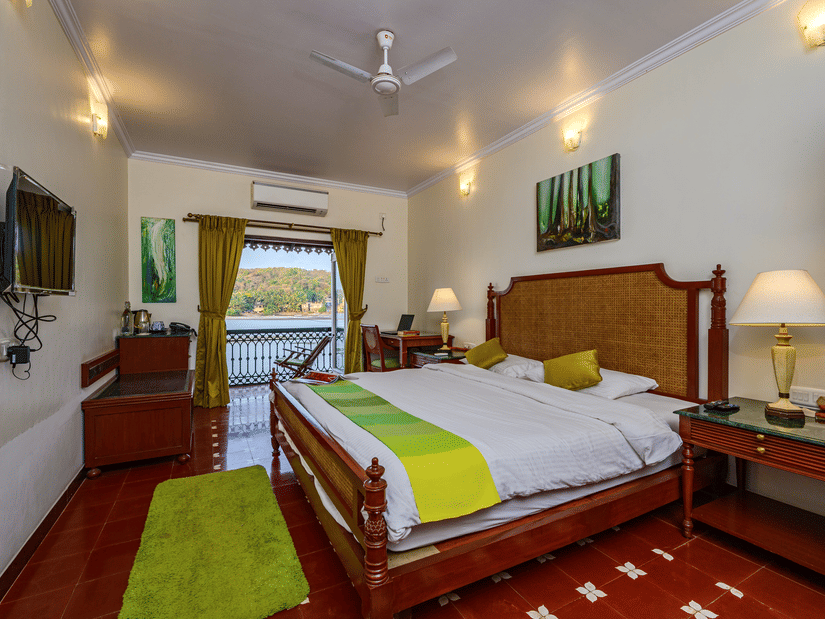 A double bed with balcony and marble side table in Cones - River View Room at neemranas three waters