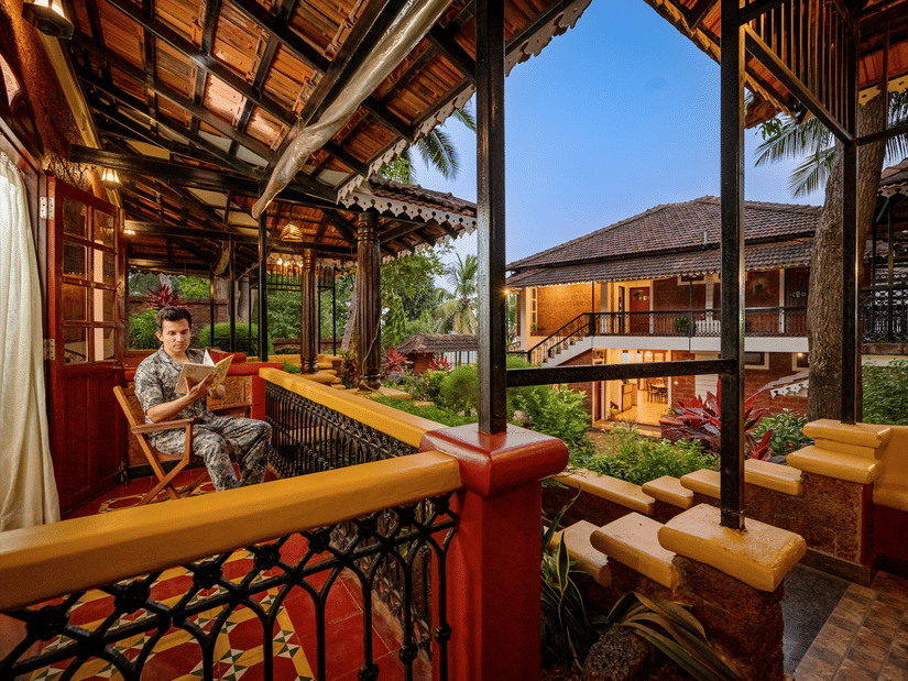 A guest sitting on a rocking chair and reading a book in a hotel room balcony - Neemranas Three Waters - 20th century, Betul, South Goa