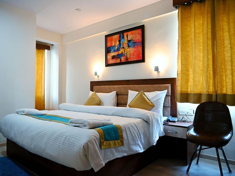 The king size bedding with white sheets in the triple bed room - Panchvati Inn Badrinath
