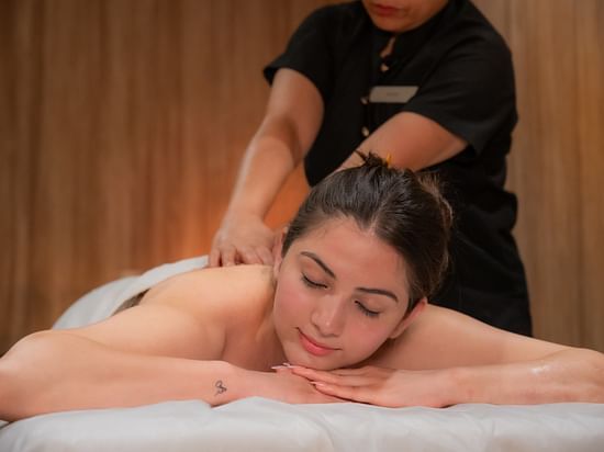An image of a women receiving back massage in a room which has other massage and spa products - The Manor Luxury Apartments, Shimla