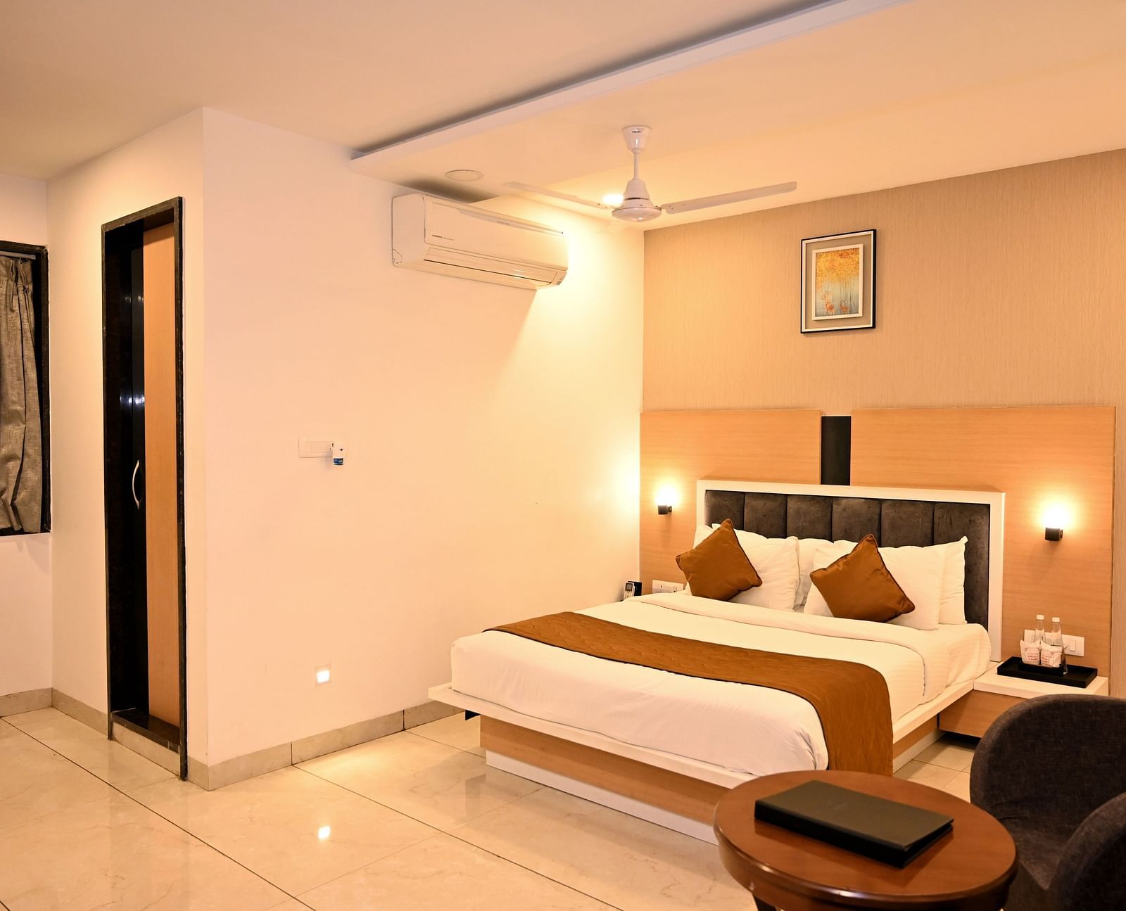A stylish bedroom featuring a large bed with a green headboard and textured wall art - TGI Insignia, Bhopal