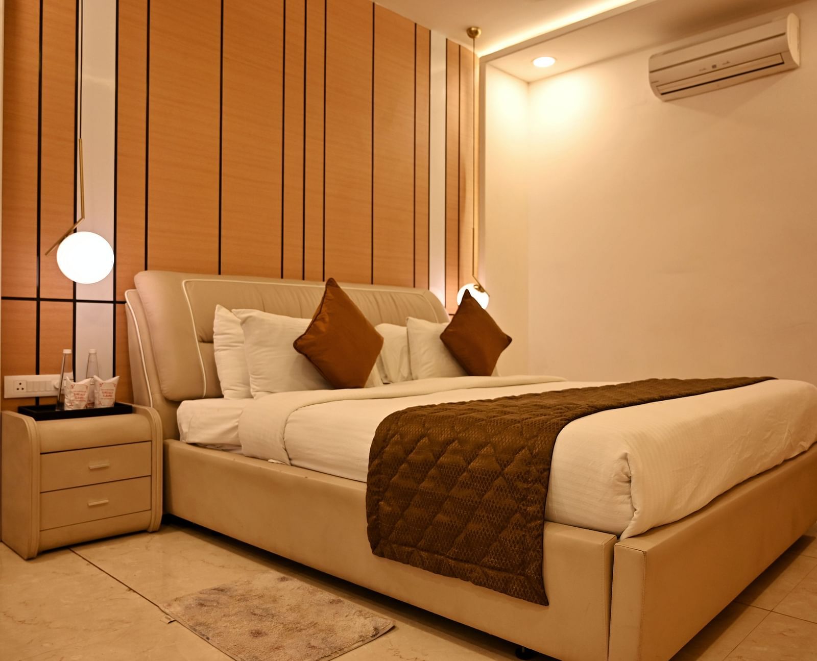 An elegant bedroom with a beige upholstered bed and a unique pendant light - TGI Insignia, Bhopal