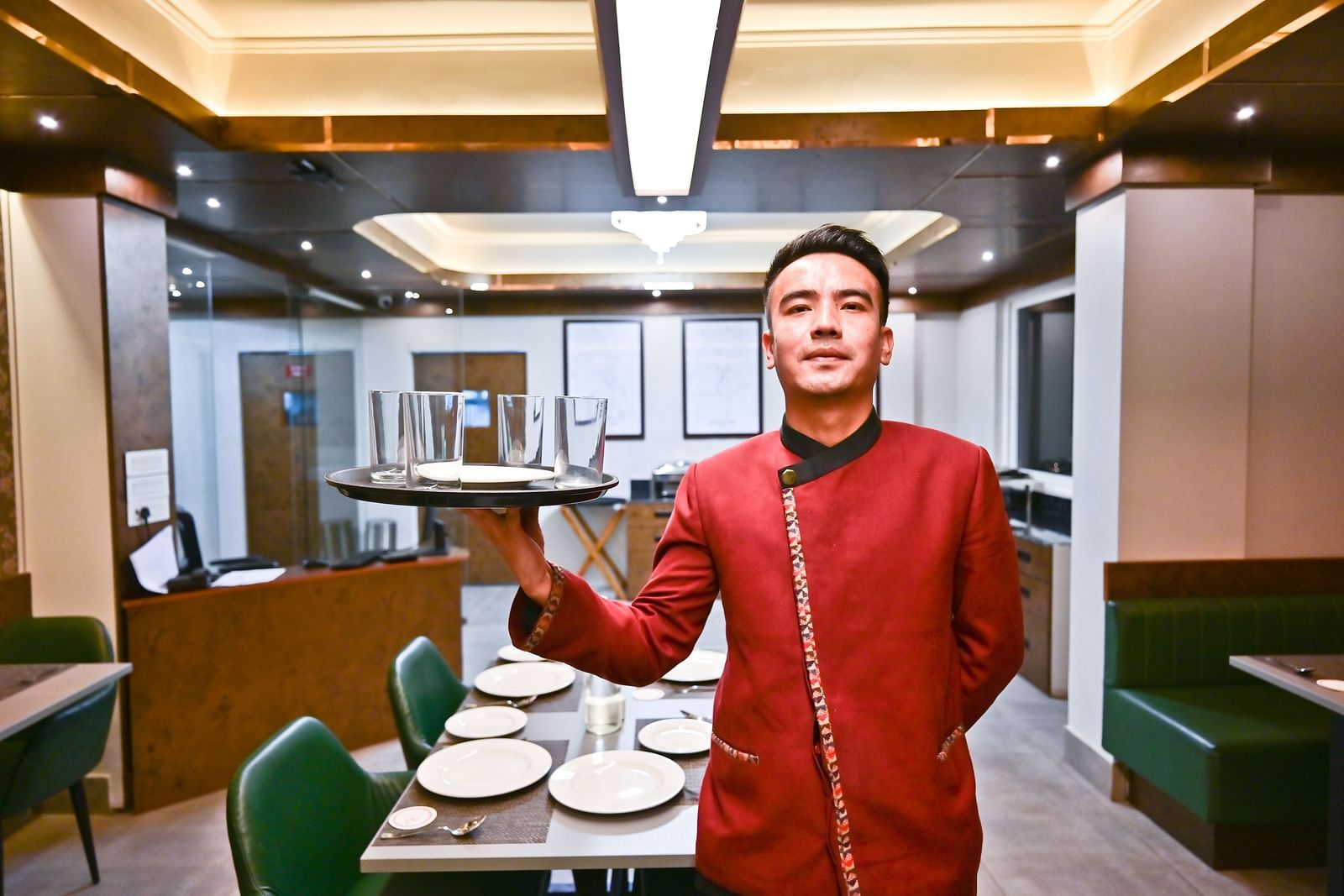 The waiter elegantly holding the dishes, prepared to serve, at The Soma Hotel by Avianna Group, Darjeeling
