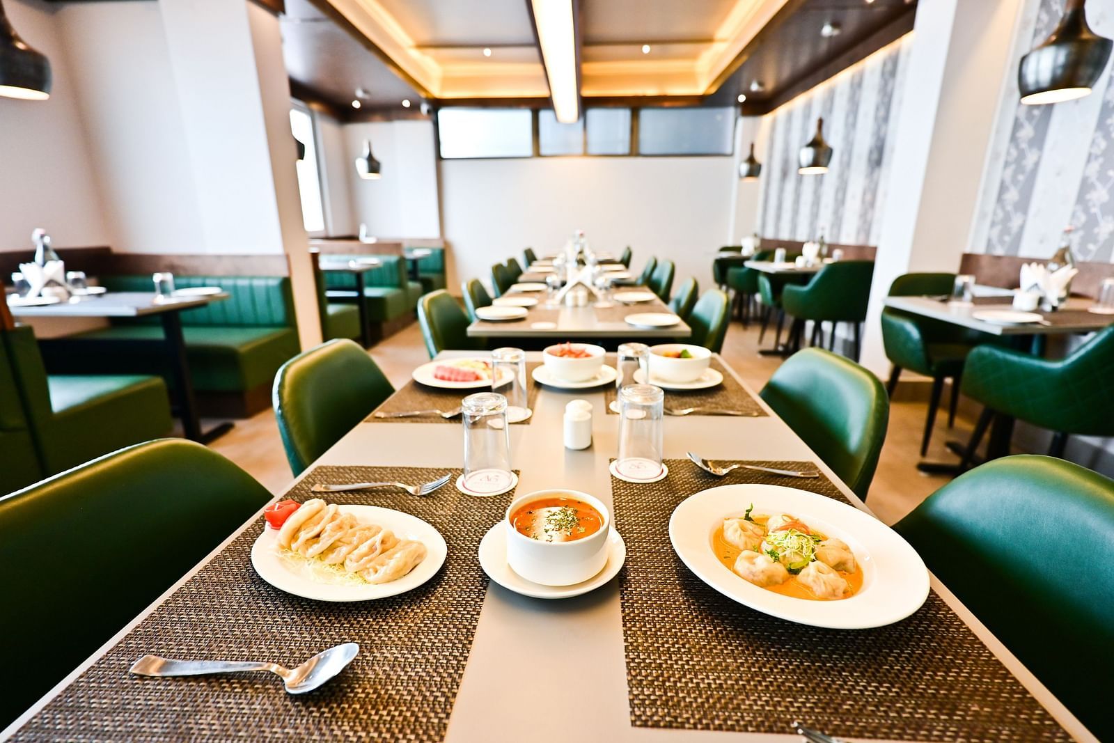 A spacious restaurant with wooden tables and chairs, featuring a variety of dishes set on the tables at The Soma Hotel by Avianna Group, Darjeeling