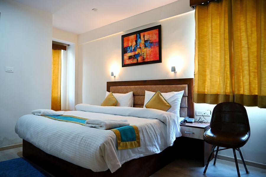 The king size bedding with white sheets in the triple bed room - Panchvati Inn Badrinath