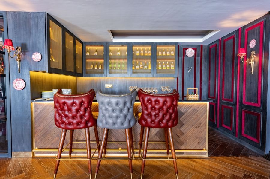 Two red coloured high chairs place in front of a bar counter - The Manor Luxury Hotel, Shimla