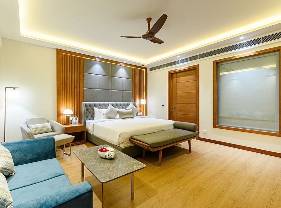 Interiors of one of the bedrooms at our presidential suite in Pushkar featuring a bed, a blue sofa and other furniture 5761